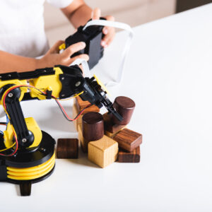 Happy Asian little kid boy using remote control playing robotic machine arm for pick up wood block, Funny child learning successful getting lesson control robot arm, Technology science education
